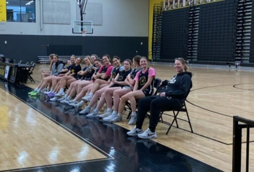 Katie Smith poses on the bench with the Upper Arlington girls basketball team. Smith has been serving as a volunteer assistant coach o for the Golden Bears.